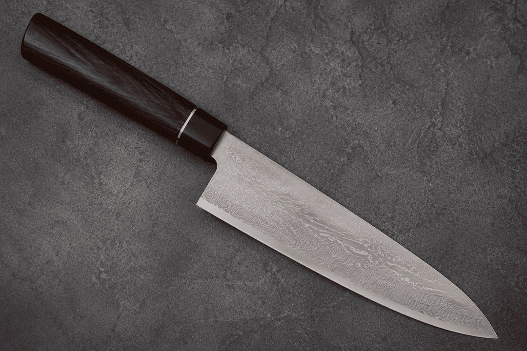 Gyuto mit dunklem Holzgriff auf grauem Steinuntergrund